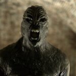 Black biomechanical creature with exposed teeth and open mouth