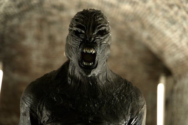 Black biomechanical creature with exposed teeth and open mouth