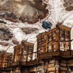 Ornate baroque library with towering wooden bookshelves and painted ceilings